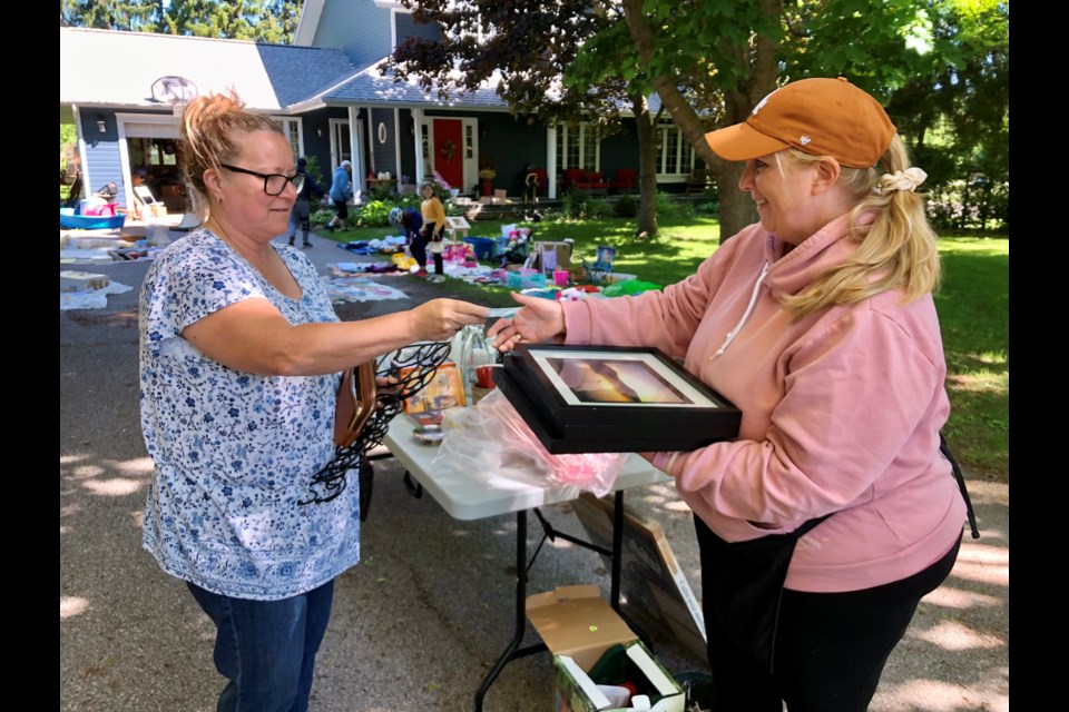 Jeannie Inglis buys picture frames at Heather Oliver's garage sale in Shanty Bay.