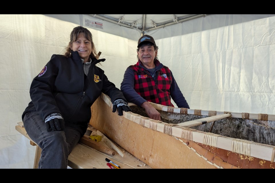 Master builder Chuck Commanda and his assistant Joanee Dumoulin take a break from builing a birch bark canoe at Elmvale District High School.