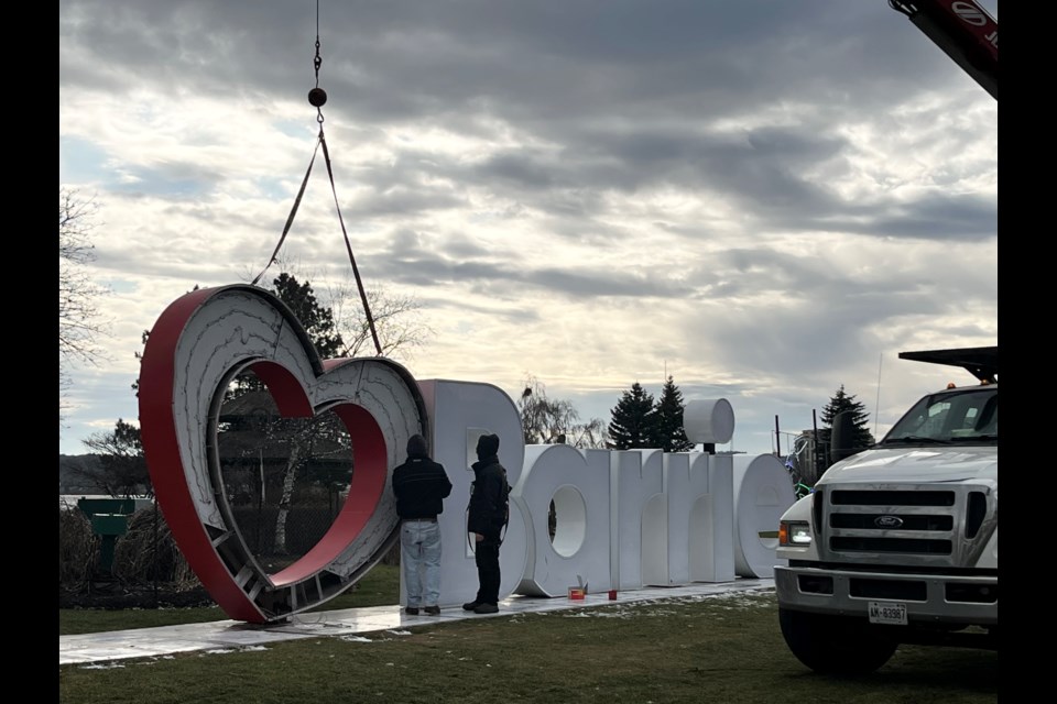 Workers reinstall the heart from the Love Barrie landmark sign at Heritage Park, Friday afternoon. 