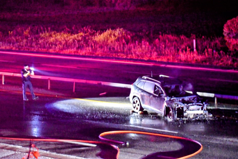 An OPP officer takes a look at the scene of a two-vehicle crash on July 6 that sent multiple people to hospital and resulted in one vehicle going up in flames.