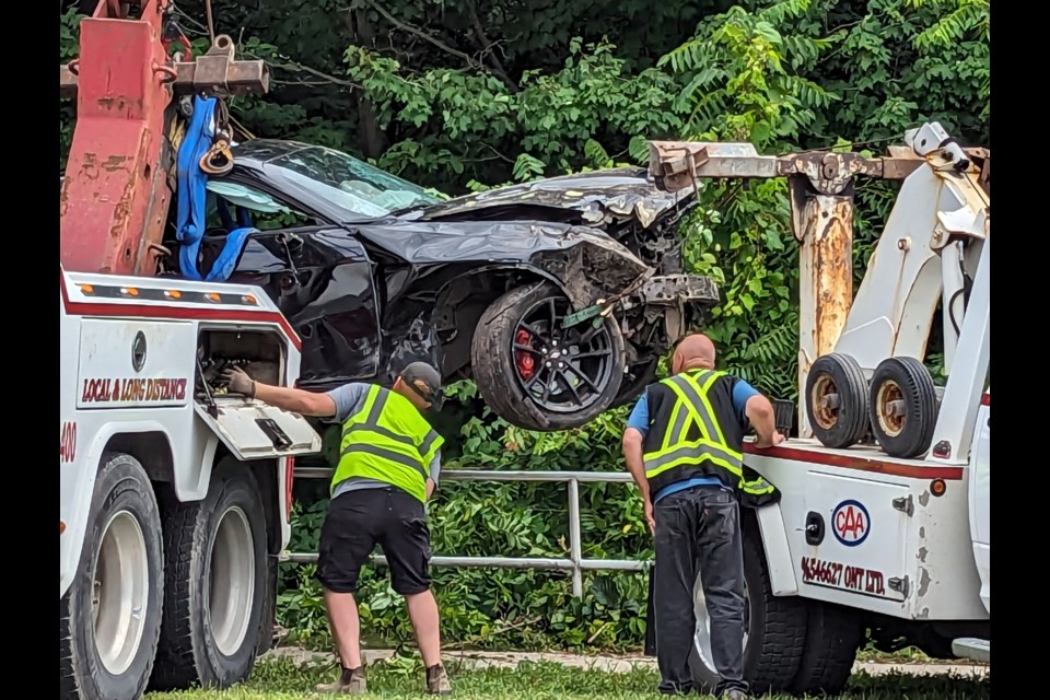 Crews from Classic Towing work to remove a heavily damaged car from the scene following a single-vehicle crash on Anne Street North in Barrie, Sunday.