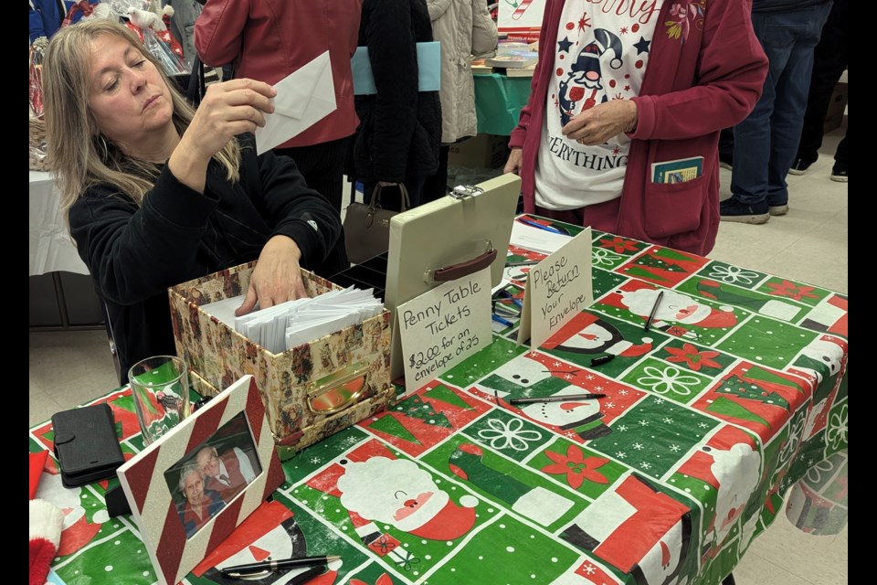 Angel Gowan checks an envelope at the Penny Table with a photo of her parents, Edith and Allan Clements, in the bottom left of this photograph.