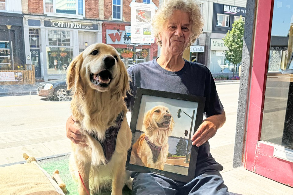 Rob McCormack sits with his beloved dog Sally after being presented her portrait by local artist Cherin Harris Tuck at his shop on Dunlop Street East on Aug. 7.