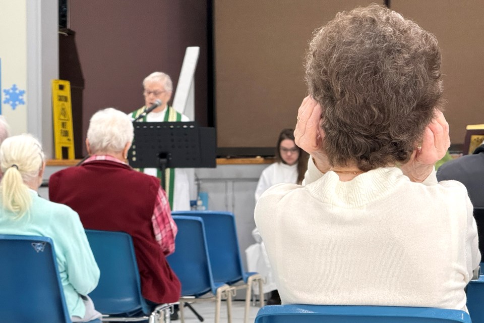 A worshiper cups her ears as she strains to hear the service held in the auditorium of Trinity Anglican Church on Collier Street in Barrie on Sunday, Jan. 28, 2024. The service was moved due to severe vandalism inside the church recently.