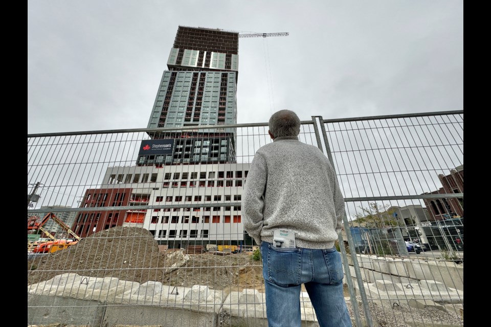 A man peers up at the Debut Waterfront Residences building, which is under construction at Dunlop Street West and Mary Street in downtown Barrie.