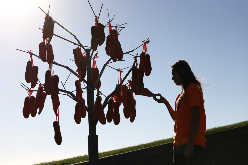 Emily Akiwenzie looks at an unnamed sculpture to honour residential school survivors, created by artists Josie Fiegehen and Sam ZH, set up at the base of the Spirit Catcher sculpture at Barrie's waterfront on Monday in recognition of the National Day for Truth and Reconciliation. It is constructed from steel and 1950s wooden shoe forms.