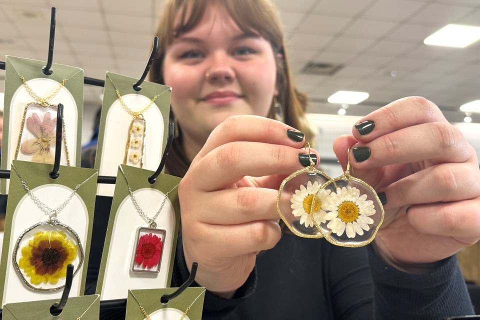 Abigail Hay shows off her earrings and pendants made with preserved flowers during the Barrie Artisan Market at the Allandale Recreation Centre on Saturday, Nov. 25, 2023.