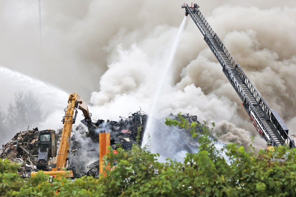 Fire crews battle a large fire in a pile of metal and other materials at a recycling facility, All Ontario Recycling, on Tiffin Street in Barrie on Monday.