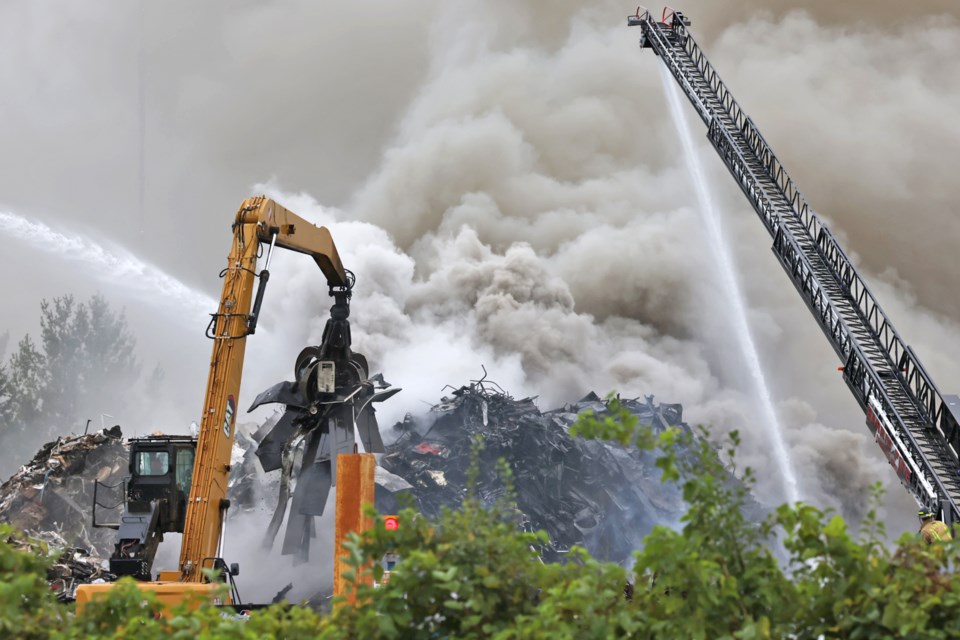 Firefighters and the facility's equipment operators battle a blaze at a metal recycling plant on Tiffin Street in Barrie on Monday, Aug. 19.