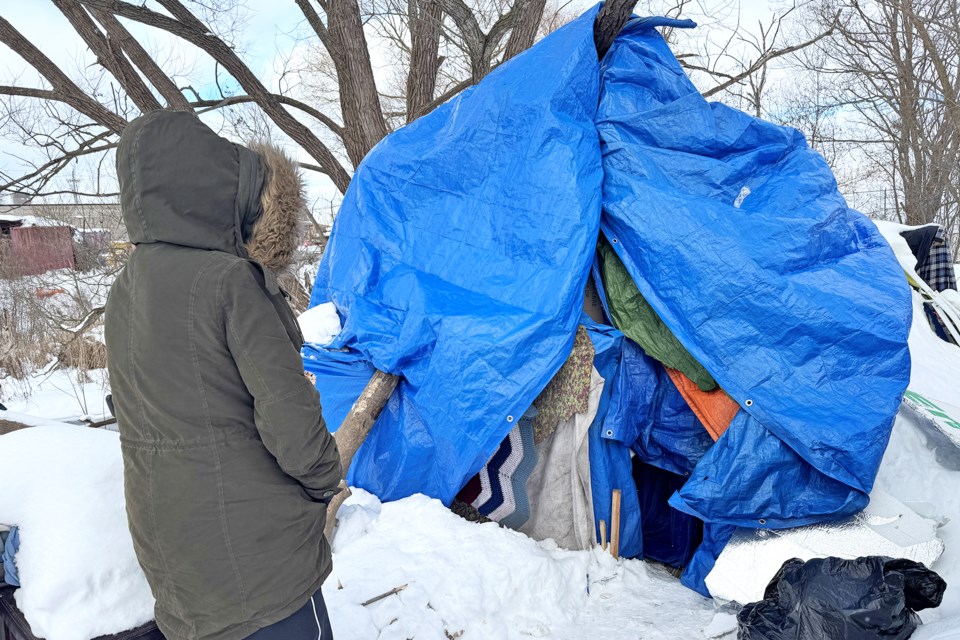 Tanya, who is homeless, stands next to her flimsy tarp shelter near Victoria and Bradford streets in Barrie on Tuesday afternoon.