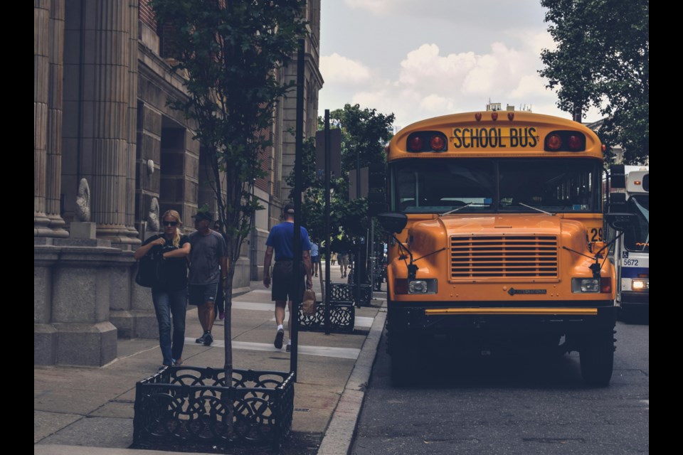 This image shows a school bus equipped with a yellow safety arm on the front bumper. 