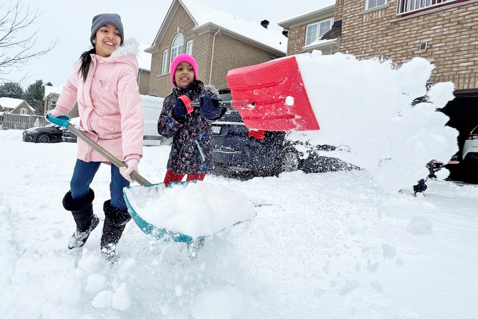 Aarna, 7, and Aadhva, 9, of Barrie, sling snow on their driveway after a big dumping of the white stuff overnight.