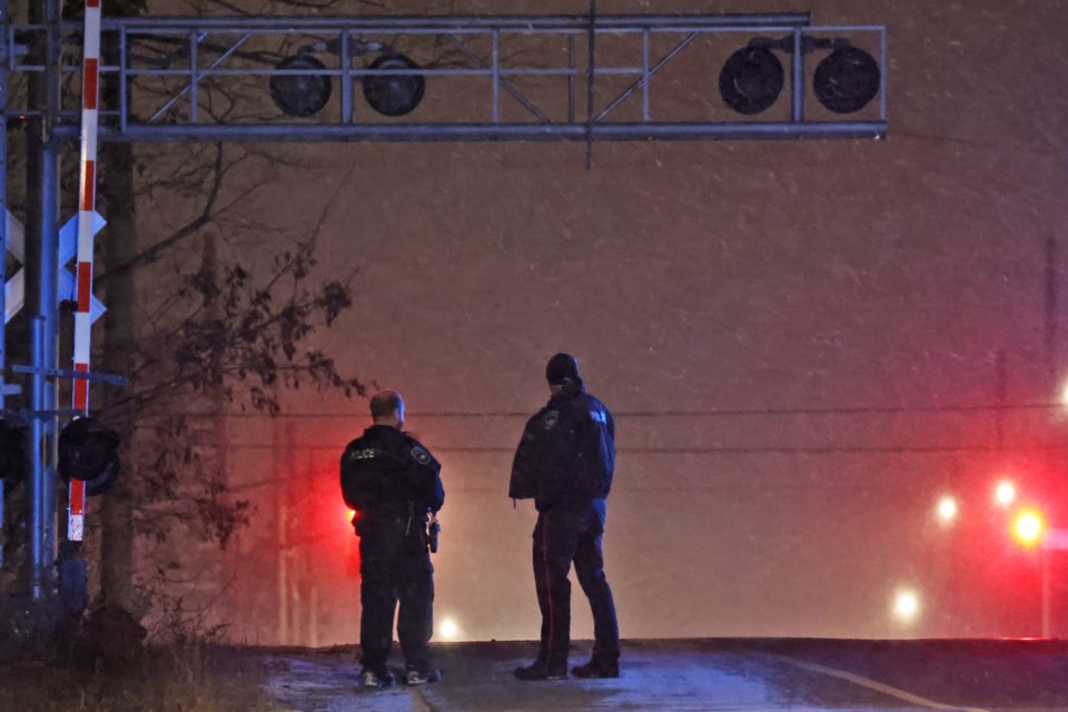 A pair of Barrie police officers watch events unfolding with a heavy police presence at the area of Mapleview Drive East and Yonge Street from the railroad tracks east of Yonge Street on Monday night. Roads have been closed in all directions.