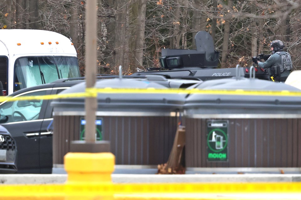 A Barrie police tactical officer is seen on top of an armoured vehicle with his rifle at the ready, as a person with a gun is inside a recreational vehicle behind a Bayfield Street business on Thursday afternoon. A cluster of bullet holes can be seen on the upper part of the RV's windshield.