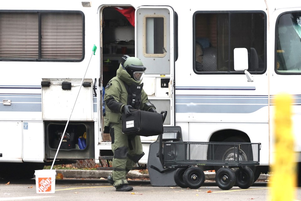 A bomb squad officer carries a protected box with "frag bag" written on the side, after he exited the RV at the centre of a 16-hour police standoff on Bayfield Street in Barrie which ended peacefully at 4 a.m. this morning.