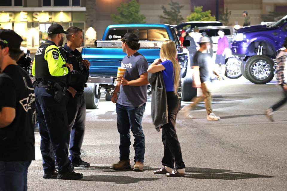 Police officers speak to people as they keep an eye on an unsanctioned truck rally held in the rear parking lot of Park Place on Mapleview Drive East in Barrie on Saturday night.