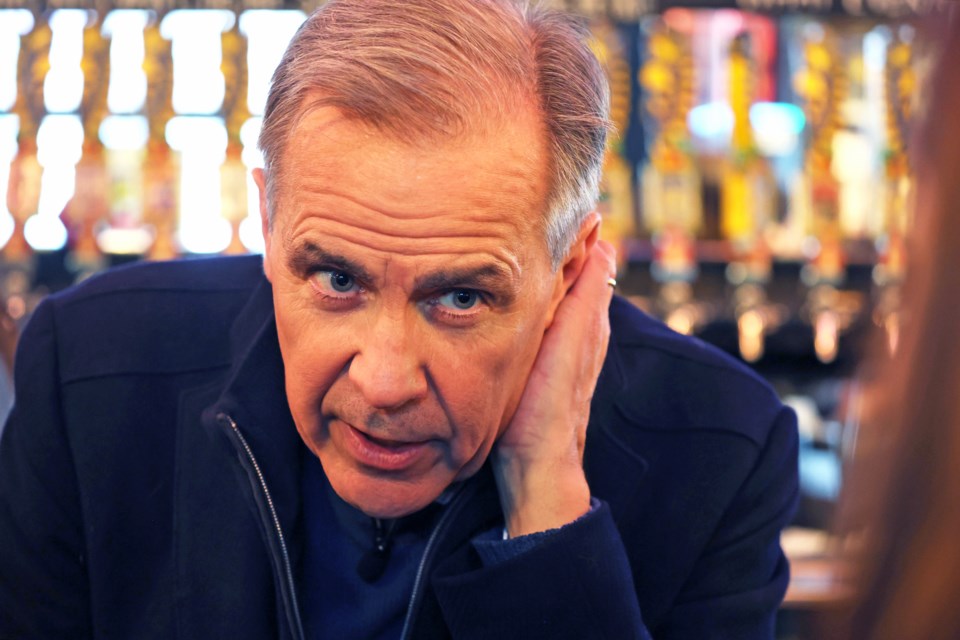 Federal Liberal leadership candidate Mark Carney leans on a bar and listens to a local party member while visiting with supporters at Flying Monkeys Craft Brewery in downtown Barrie on Friday.