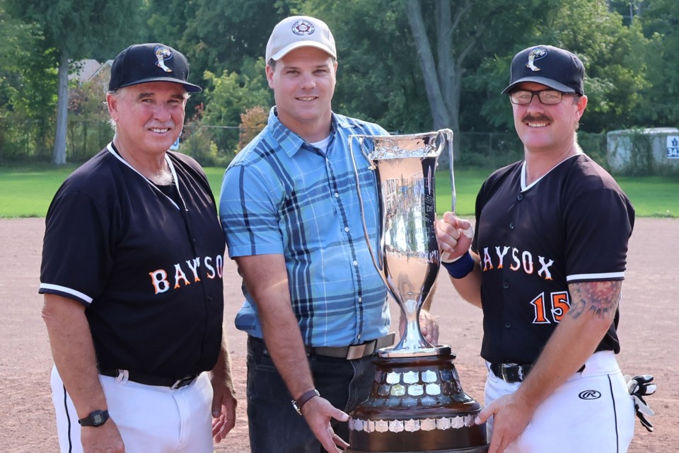 North Dufferin Baseball League secretary Scott Anderson (centre) presents the Strother Cup to Don Bartley and Ryan Bartley of the Owen Sound Baysox after their 9-6 Game 5 win over the Ivy Rangers 