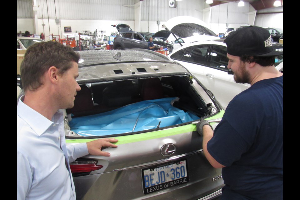 Zenetec general manager William Monteith, left, watches as an employee cleans up one of 19 cars damaged in a span of three days. Shawn Gibson for BarrieToday