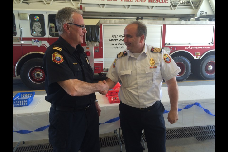 North Bay Fire Chief Jason Whiteley congratulations Randy Vezina on his retirement.