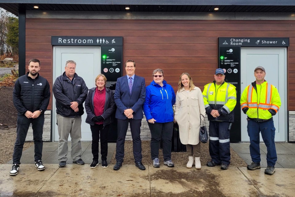 Mayor Noon (middle, blue suit), Councillor Irene Smit (left of Noon), and Councillor Jordy Carr (right of Noon) are joined by municipal staff members to unveil the new bathroom at the dock.