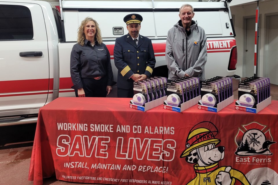 Jennifer Beam, Chief Steph Amyotte, and East Ferris councillor Terry Kelly take time for photo with today's donation of life-saving alarms