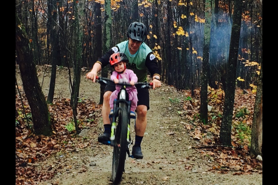 Travis and 18-month old Calliope Murphy go for a spin at Three Towers Trail Network grand opening.