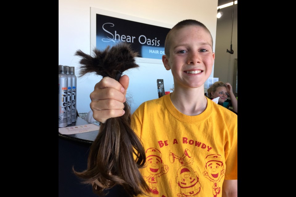 Charlie Pipe holds up his long locks which were cut on Thursday.  Photo courtesy Bob Pipe.  