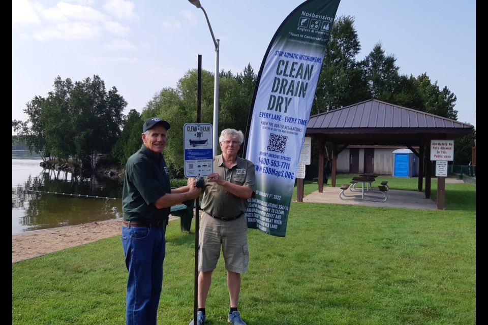 Nosbonsing Anglers and Hunters President Wilfred Weiskopf, left, and club member Barry Schruder put up one of nine Clean, Drain and Dry signs on Lake Nosbonsing. The club plans to erect 40 signs in Parry Sound and Nipissing districts to encourage boaters to take steps to prevent the spread of invasive species.