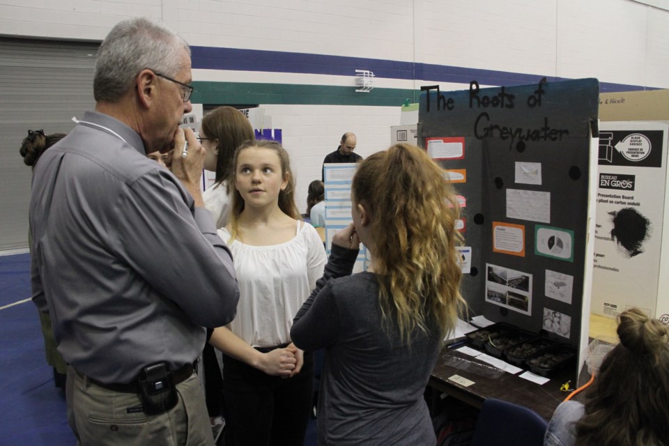 Science fair judge Bill Hagbourg speaks with some students about their project.  Photo by Chris Dawson. 