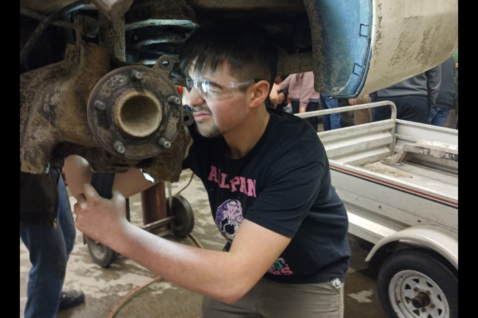 A student works on a car's brakes.