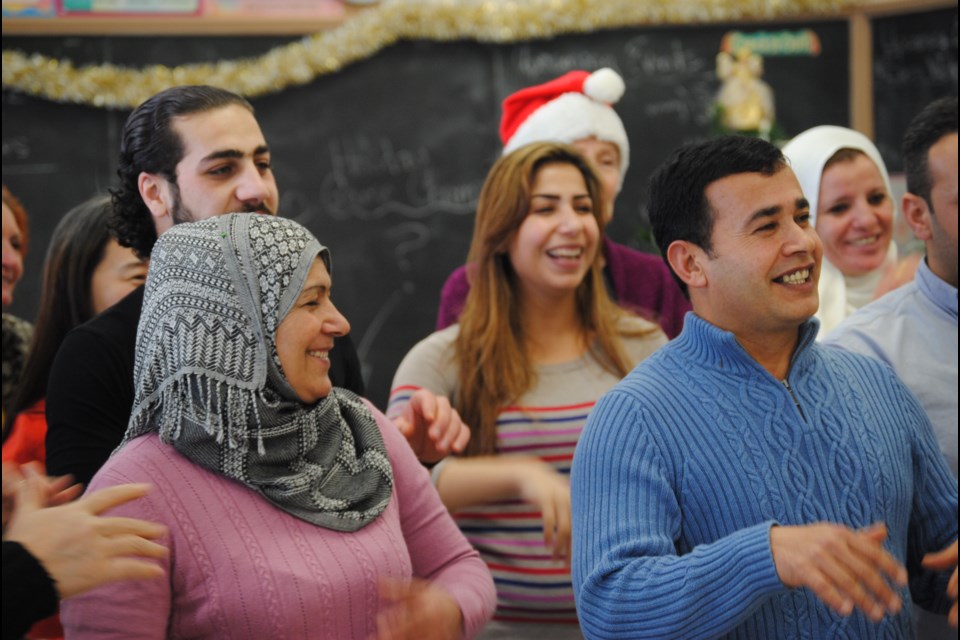 Led by ESL teacher Melanie McVeety, Syrian refugees sing the Twelve Days of Christmas. Photo by Stu Campaigne.