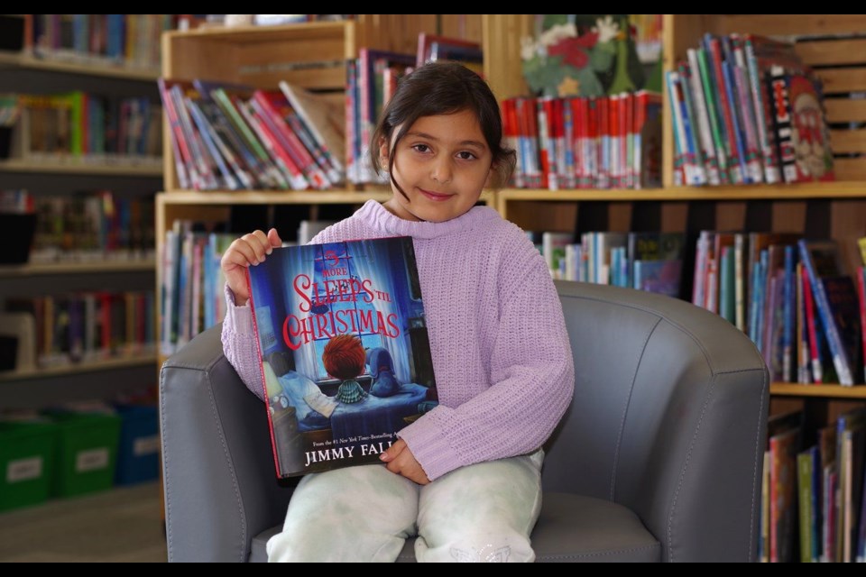 Aiya Roadknight-Amer, a 7-year-old grade 2 student at Sunset Public School in North Bay displays the latest book the Powassan library is showcasing for this year's Christmas Story Walk project. Rocco 