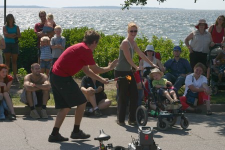 Ben Burland tries to recruit a young helper for his fire juggling routine.