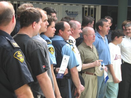 Police officers, emergency personnel and several civilians pose for a photo before getting their heads shaved.