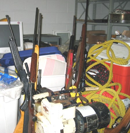 These four guns sit among other pieces of property confiscated by the OPP after an arrest . Photo by Phil Novak.