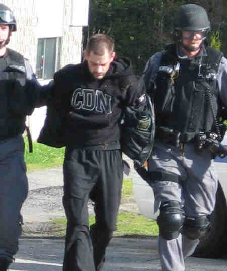 Daniel Michel Choquette is escorted to a police cruiser by members of the North Bay Police Service Emergency Response Team.