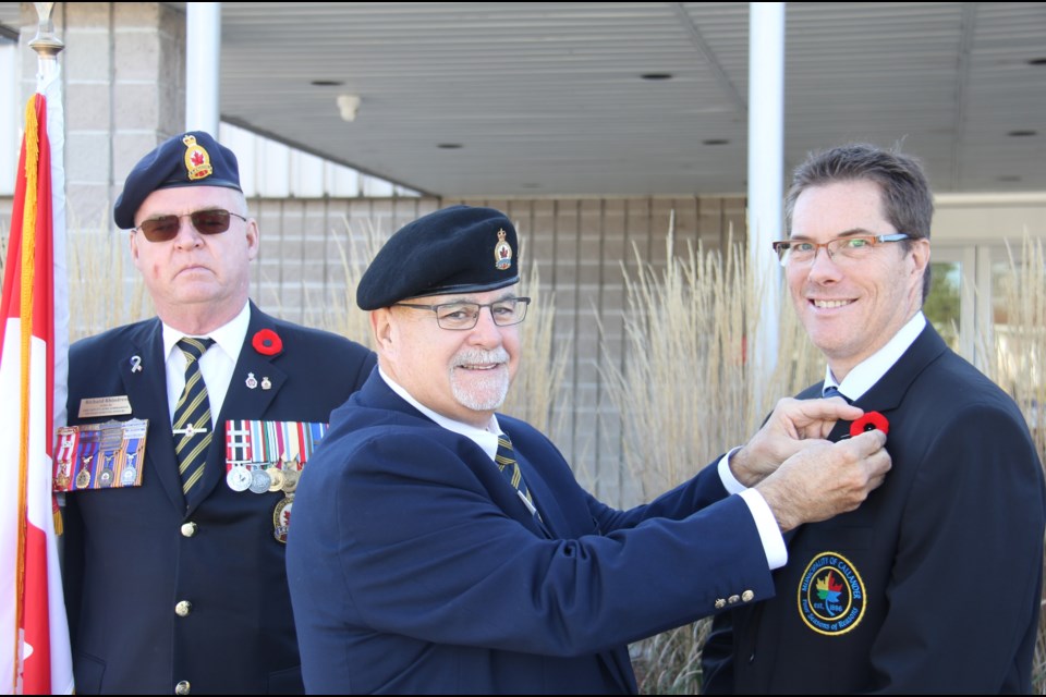 Legion President Ron Devost pins the first poppy on Callander Mayor Robb Noon while Richard Rhindress looks on.
