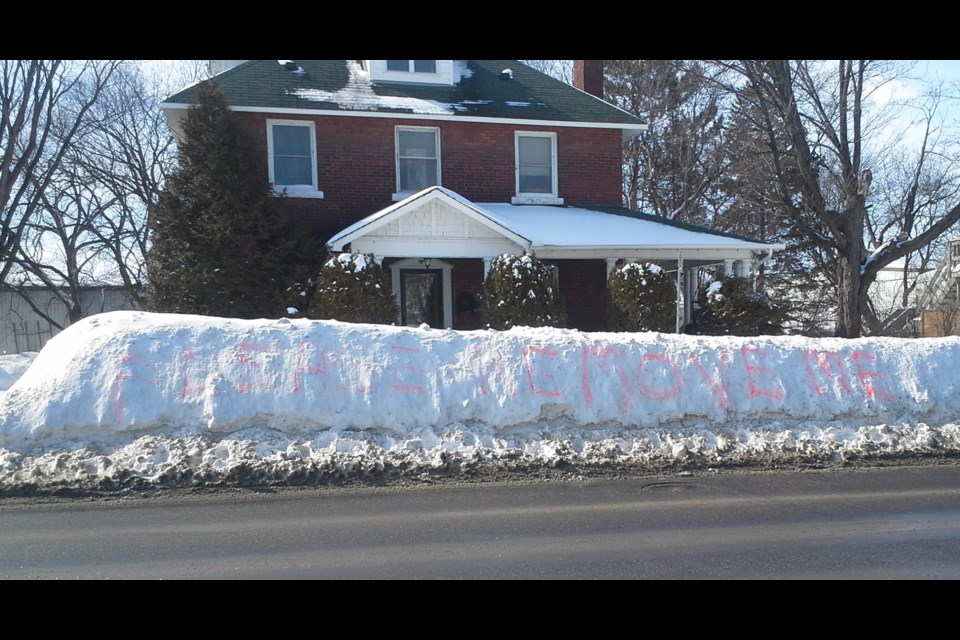 Someone has spraypainted "PLEASE REMOVE ME" on a snowbank on Main St. W.