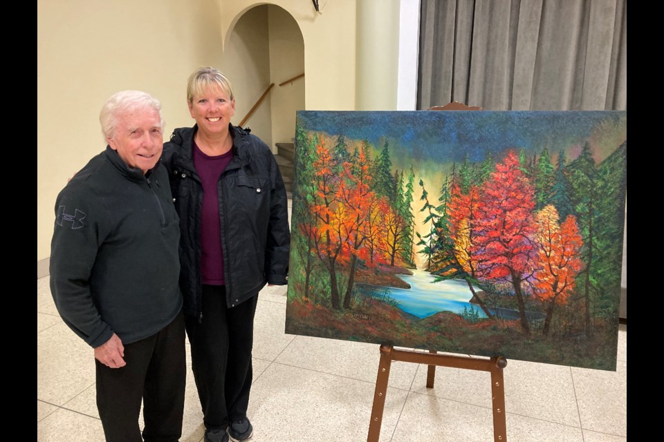 Jack Lockhart poses with Linda  Hegyi beside her purchase of one of his paintings