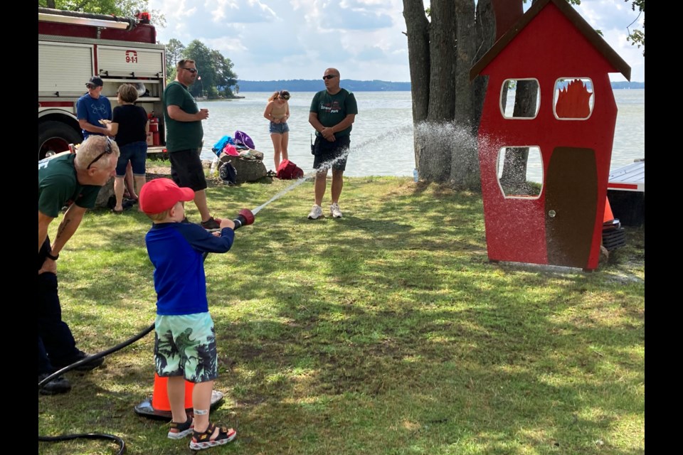 Five-year-old Finlay Muirhead takes aim at “flames” visible in the windows of a wooden cut-out during Sirens in the Park 