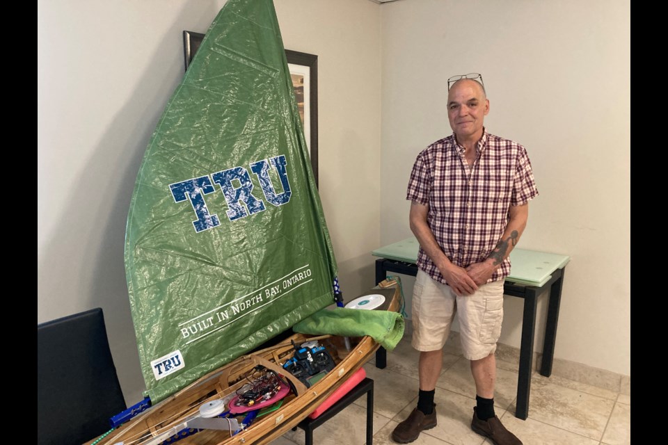 Raymond Belec stands beside the robotic boat he built for the International Robotic Sailing Regatta in Massachusetts