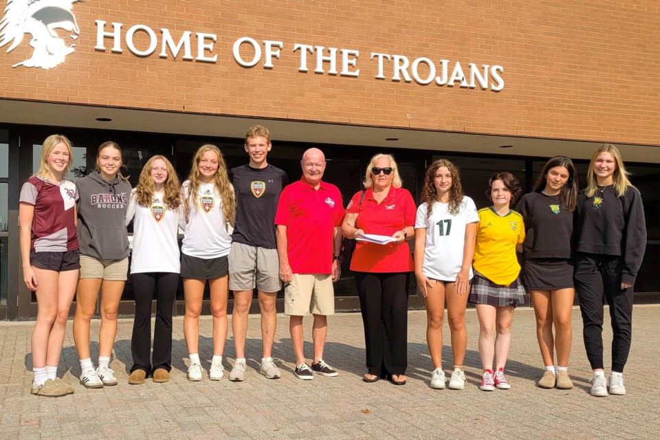 Sue Knight, President of North Bay Youth Soccer, (in red, right), and Paul Cook (in red, left) pose with the city’s up and coming soccer stars before donating $20,000 to local high school soccer programs 