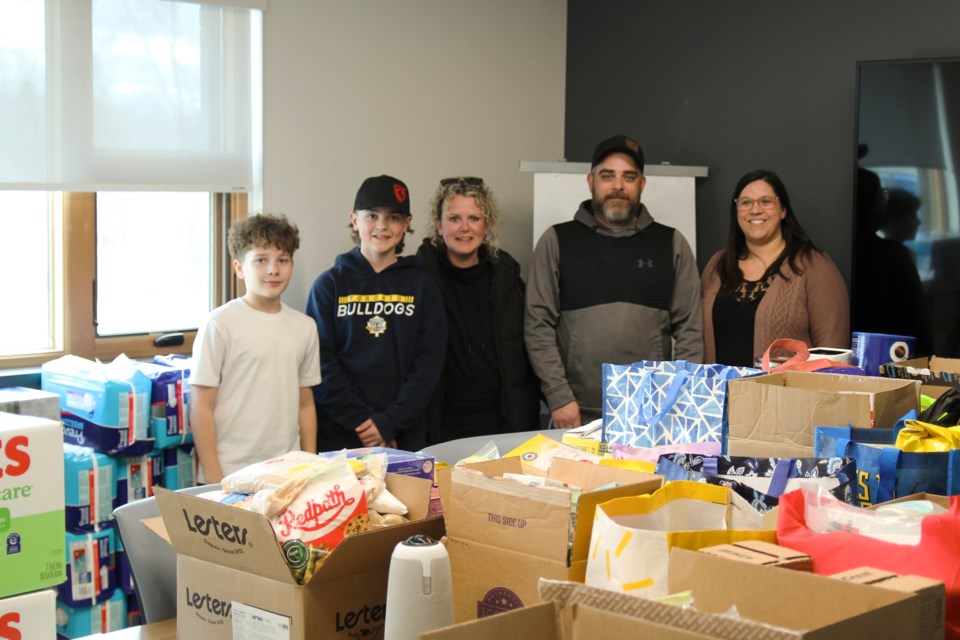 Jackson Purdon, Sawyer Gedanitz, Trista Nodwell, Mike Purdon, and Kelsey Ellis take a moment from hauling in donation to pose by the bounty of gifts