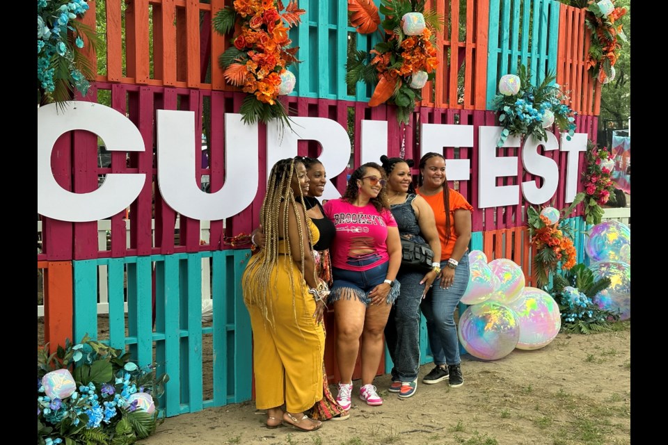 Friend group pose in front of floral CURLFEST sign