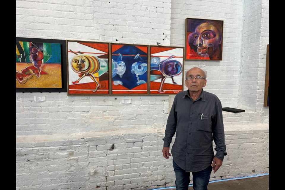 Artist, PhD professor and asylum seeker Roger Miranda stands in front of some of his art pieces.