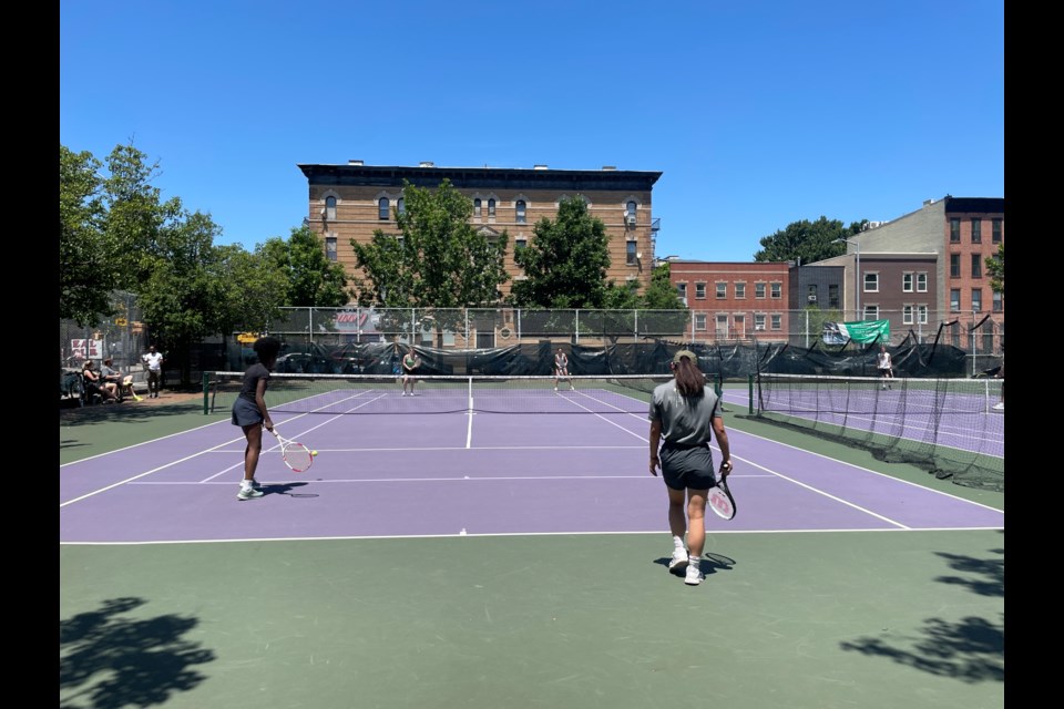 Four tennis players on the courts at Jackie Robinson Park Playground.