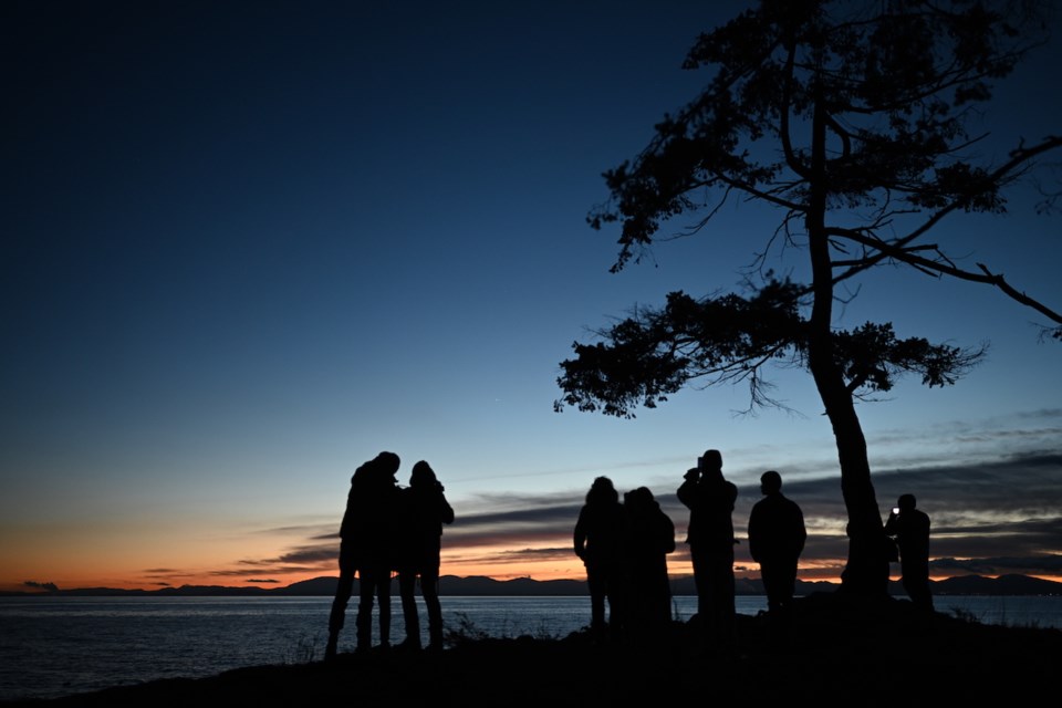 Silhouettes of people standing at the Cape at sundown