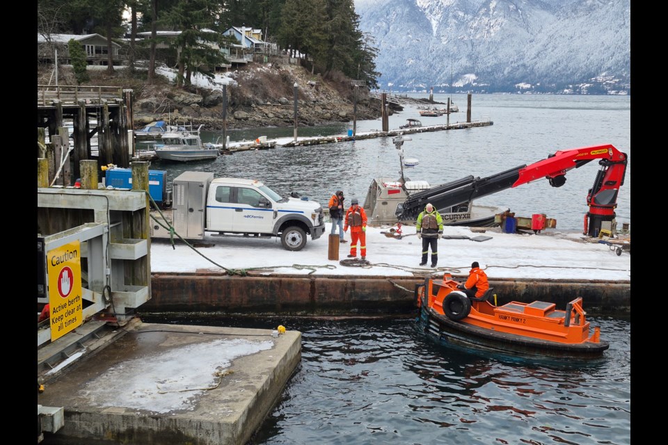 Repair crews busy at work fixing the Snug Cove Ferry Terminal on Wednesday afternoon. Workers travel between the Snug Cove Dock and repair barge aboard the Hanky Panky 2.