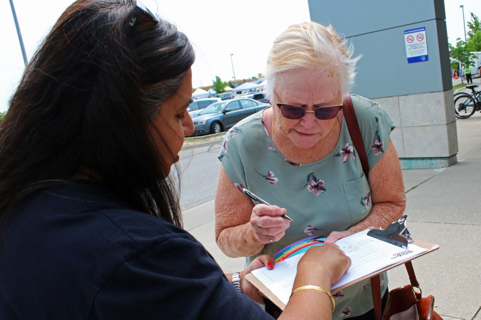 Nina Brown vice president of CUPE Local 905 helps Judy Burns, as she signs a petition supporting workers at the Bradford West Gwillimbury Public Library, outside the library on Saturday, June 10, 2023.